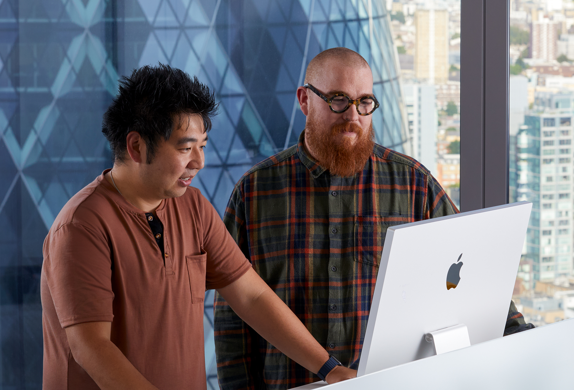Dos empleados de Apple colaborando en un iMac.