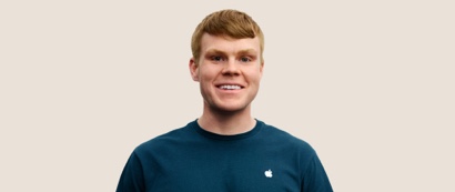 Portrait d’un membre de l’équipe Apple Retail souriant, avec des cheveux blond foncé et courts.