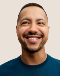 Portrait d’un membre de l’équipe Apple Retail souriant, avec des cheveux courts de couleur foncée et une barbe.