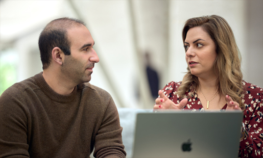 ديزيريه، جالسة أمام جهاز MacBook، تتحدث مع زميلٍ لها