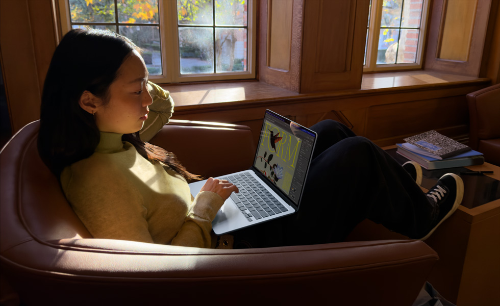 Osoba sedící v křesle používá MacBook Air