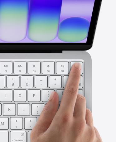 MacBook Neo i färgen silver, en persons finger vilar på Touch ID-sensorn i tangentbordets övre högra hörn
