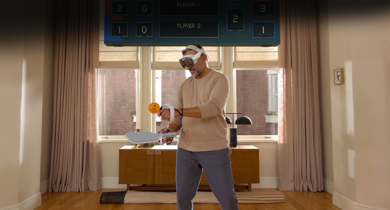 一位男士邊戴著 Apple Vision Pro，邊拿著 Sony PlayStation VR2 Sense 控制器在玩：《Pickle Pro》，空間計分板就在他的頭上