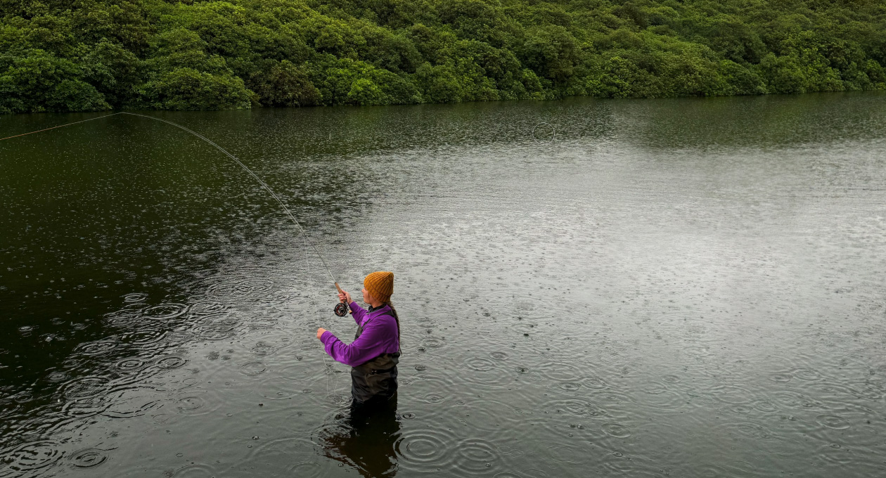 Photo d’une femme pêchant à la mouche dans un lac, l’outil Pixelmator Pro supprimant un objet indésirable en arrière-plan, surligné en jaune